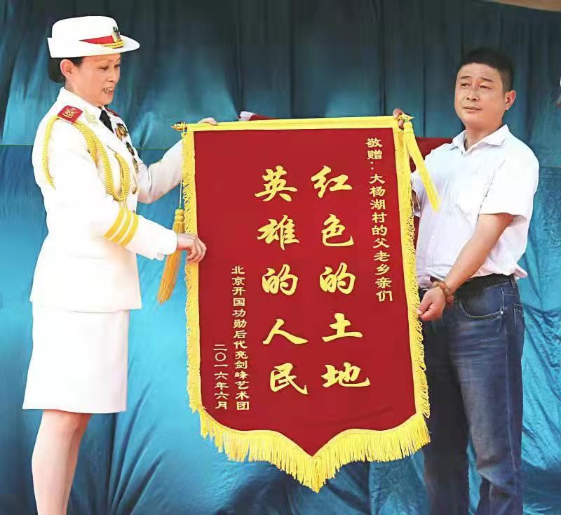 2016年，王媛媛代表开国功勋后代亮剑峰艺术团向大杨湖村赠送锦旗。